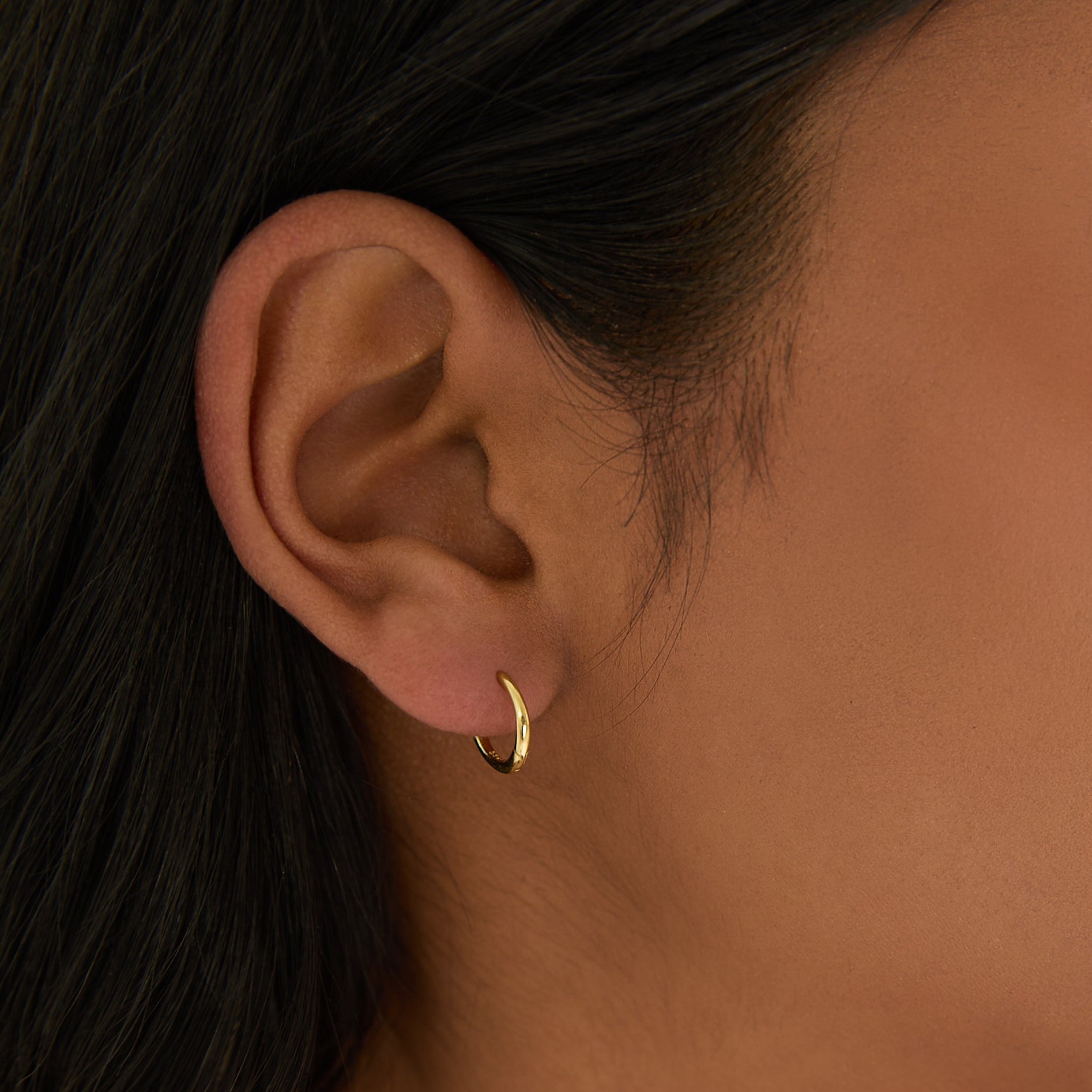 Close-up of a woman wearing a gold earring with a blurred background